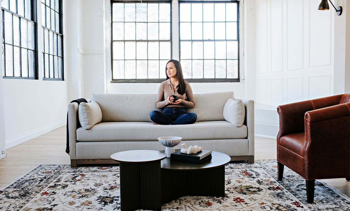 woman relaxing with coffee on custom modern sofa with exposed wood base