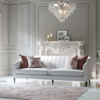 Mid century modern channel tufted grey sofa with tapered legs styled in elegant Madison room.