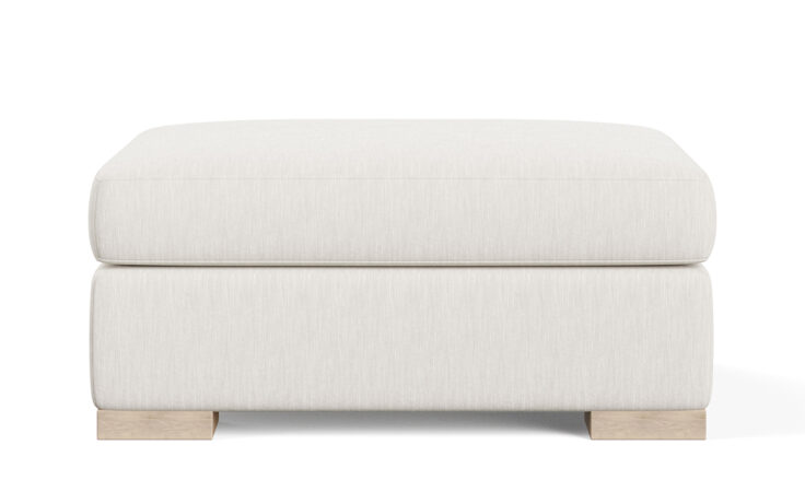 Front shot of the oversized, plush Broadway ottoman from Vogel by Chervin in a white fabric with light wood legs