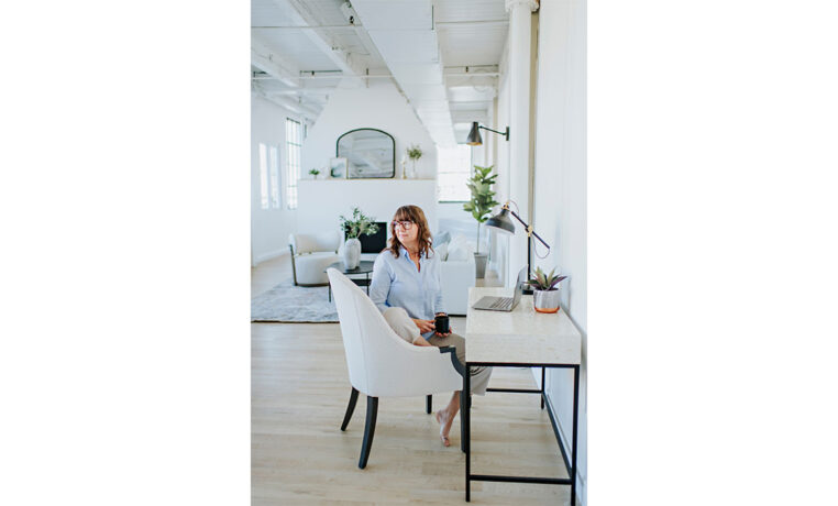 a woman working at a desk in a living room and sitting in a custom accent chair