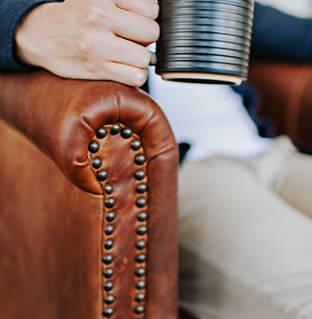 Up close detail shot of a customization nail head trim on brown leather chair.
