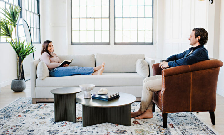 couple relaxing in a living room with one on a custom sofa and one sitting in a custom lounge chair