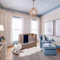Modern blue and beige nursery with a baby blue swivel chair with dark blue piping.