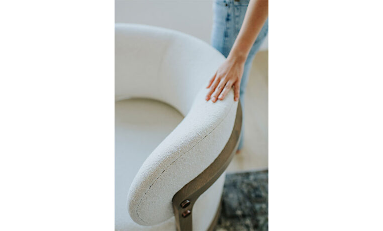 a detail shot of a white custom swivel chair with a curved back