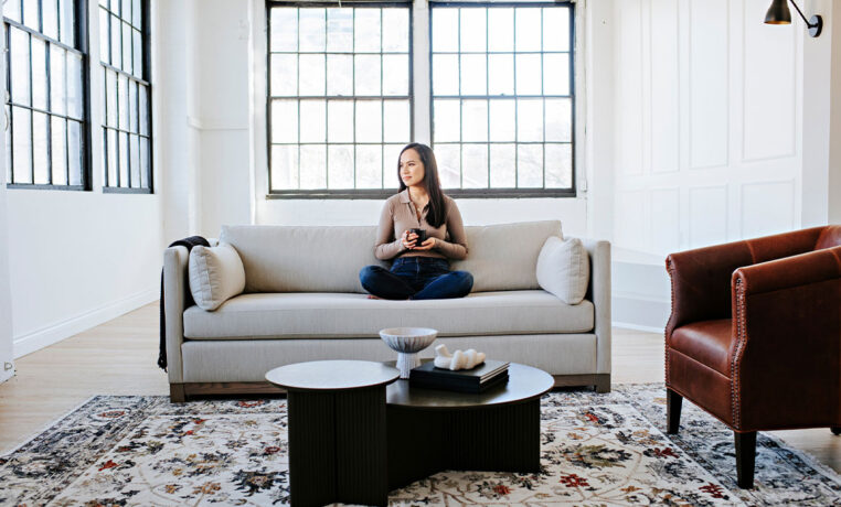 woman relaxing with coffee on custom modern sofa with exposed wood base