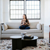 woman relaxing with coffee on custom modern sofa with exposed wood base