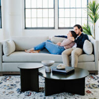 couple snuggling on a custom sofa with exposed wood base