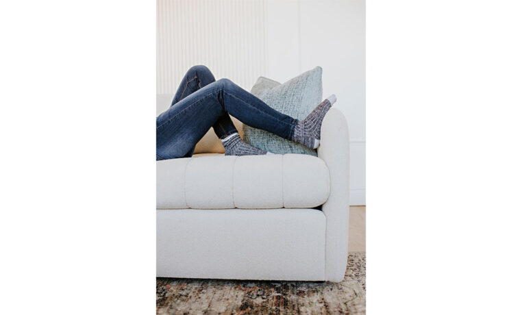woman relaxing her feet up on a white channel tufted sofa