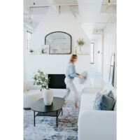 woman placing blue pillows on a white channel tufted sofa