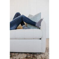 woman relaxing her feet up on a white channel tufted sofa
