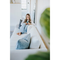 teenager texting on a white channel tufted sofa