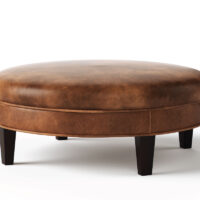 Round Carlisle ottoman from Vogel by Chervin in brown leather and espresso legs with a flat top
