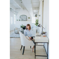 a woman working at a desk in a living room and sitting in a custom accent chair