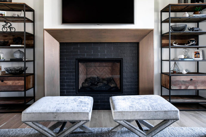 Living room with two Vogel X shape stools in front of fireplace with two open metal and wood shelves on either side of fireplace