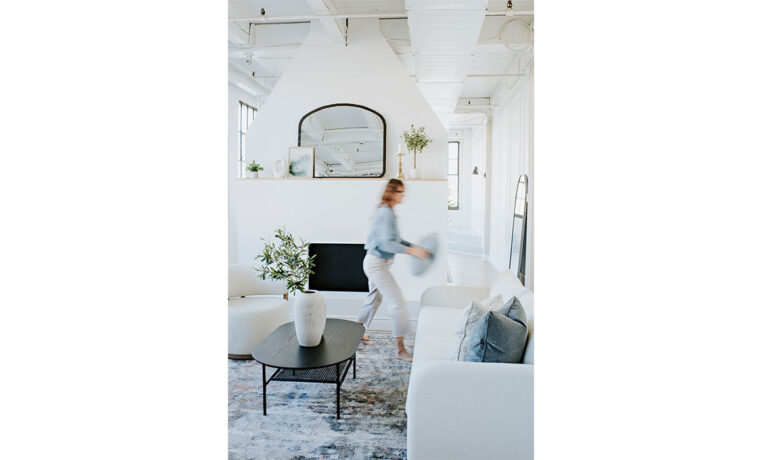 woman placing blue pillows on a white channel tufted sofa